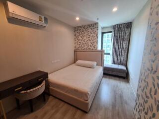 Modern bedroom with wood flooring, large bed, desk and air conditioner