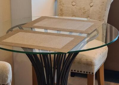 Small round glass dining table with two upholstered chairs