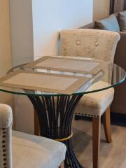 Small round glass dining table with two upholstered chairs