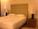 Bedroom with a large bed, two bedside tables with lamps, and textured white brick wall.