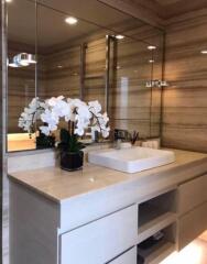 Modern bathroom with large mirror, sink, and orchid decor