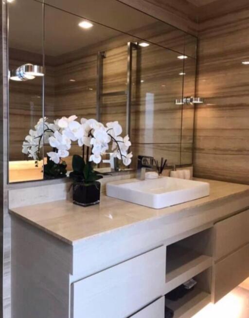 Modern bathroom with large mirror, sink, and orchid decor