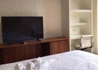 Bedroom with television, built-in shelves, chair, and bed