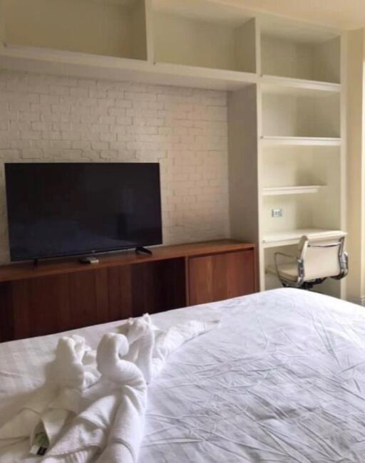 Bedroom with television, built-in shelves, chair, and bed