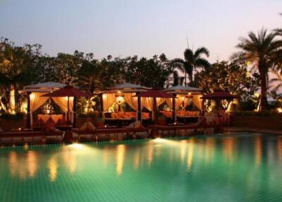 Luxurious outdoor pool area with cabanas at dusk