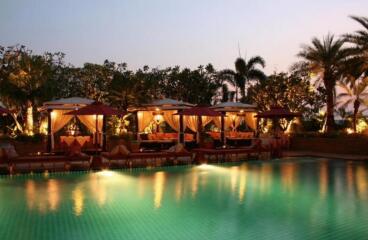 Luxurious outdoor pool area with cabanas at dusk