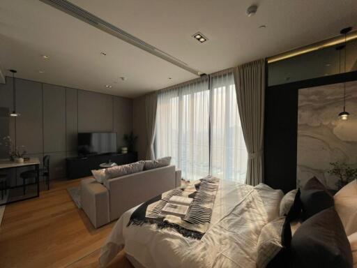 Modern bedroom with a bed, sofa, TV, work area, and large windows