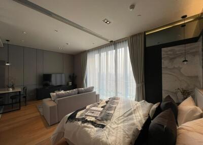 Modern bedroom with large windows, TV, desk, and seating area