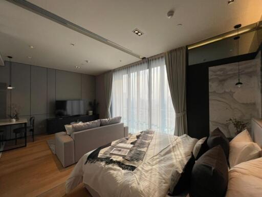 Modern bedroom with large windows, TV, desk, and seating area