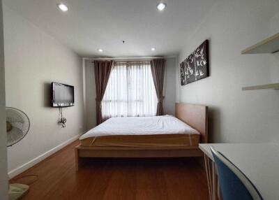 Modern bedroom with wooden furniture, wall-mounted TV, and window