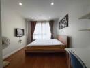 Modern bedroom with wooden furniture, wall-mounted TV, and window