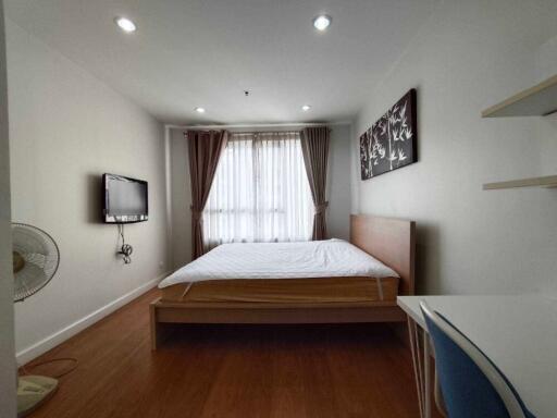 Modern bedroom with wooden furniture, wall-mounted TV, and window