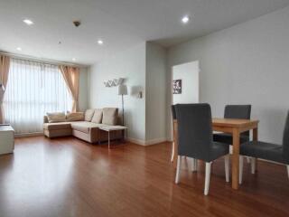 Spacious living room with wooden flooring, neutral tones, and large windows