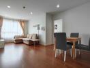 Spacious living room with wooden flooring, neutral tones, and large windows