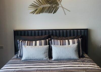 Cozy bedroom with striped bedding, decorative plant art, and good lighting