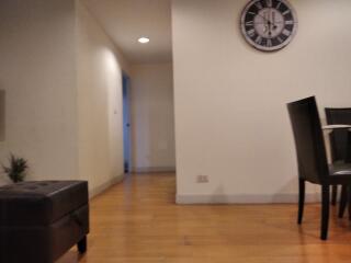 Living area with wooden floors and clock on the wall