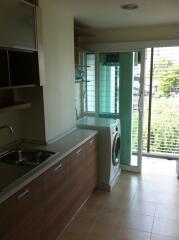 Kitchen with washing machine and balcony access