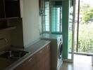 Kitchen with washing machine and balcony access