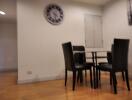 Small dining area with glass table and four black chairs