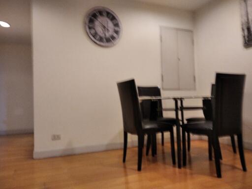 Small dining area with glass table and four black chairs