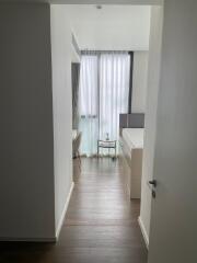 View into a bedroom with a bed, small side table, and large window with curtains