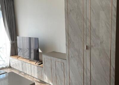 Living room with wall-mounted TV, built-in cabinet, and large window with curtains