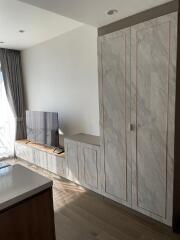 Living room with wall-mounted TV, built-in cabinet, and large window with curtains