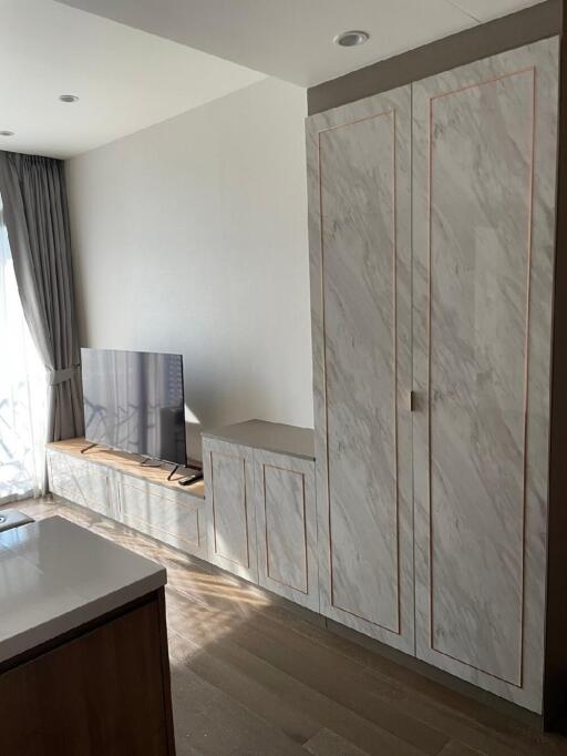 Living room with wall-mounted TV, built-in cabinet, and large window with curtains