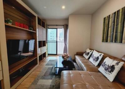 Modern living room with a large couch, TV, and a balcony view