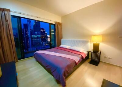 Modern bedroom with large window and city view at night