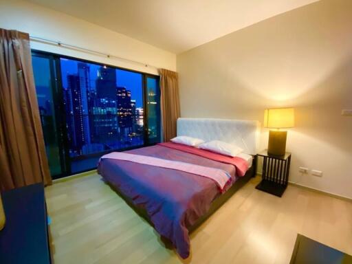 Modern bedroom with large window and city view at night