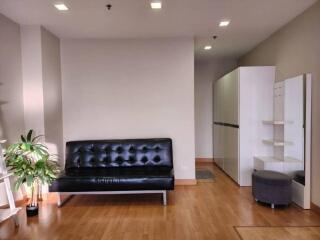 Modern living area with black leather sofa and wooden flooring