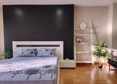 Modern bedroom with a black accent wall, bed, and shelving unit