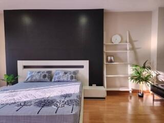 Modern bedroom with a black accent wall, bed, and shelving unit