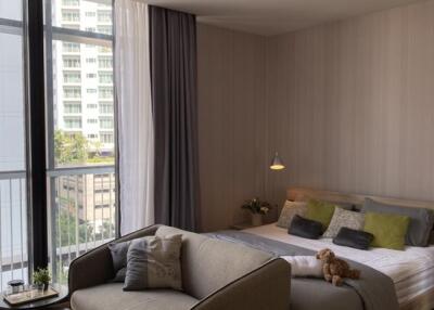 Cozy bedroom with a sofa, bed, large windows, and balcony