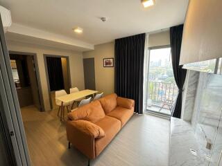 Modern living room with brown sofa, dining area, and balcony view