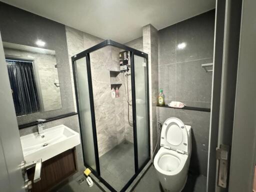 Modern bathroom with glass shower enclosure, toilet, and sink