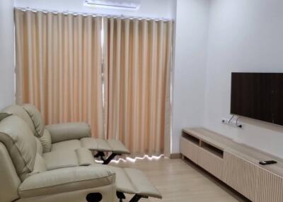 Living room with sofa, wall-mounted TV, and air conditioning