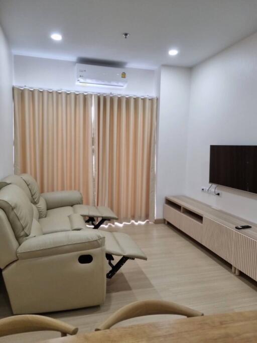 Living room with sofa, wall-mounted TV, and air conditioning