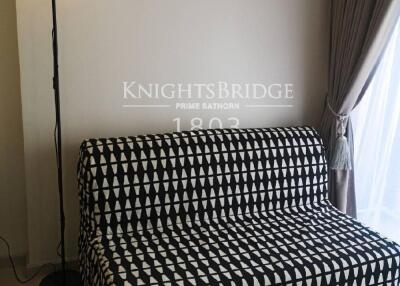 Living room with patterned black and white sofa and floor lamp