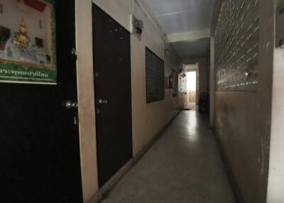 Dimly lit corridor with several doors and religious poster on the wall