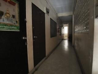 Dimly lit corridor with several doors and religious poster on the wall