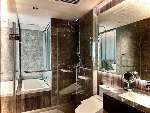 Modern bathroom with glass shower, bathtub, toilet, and vanity