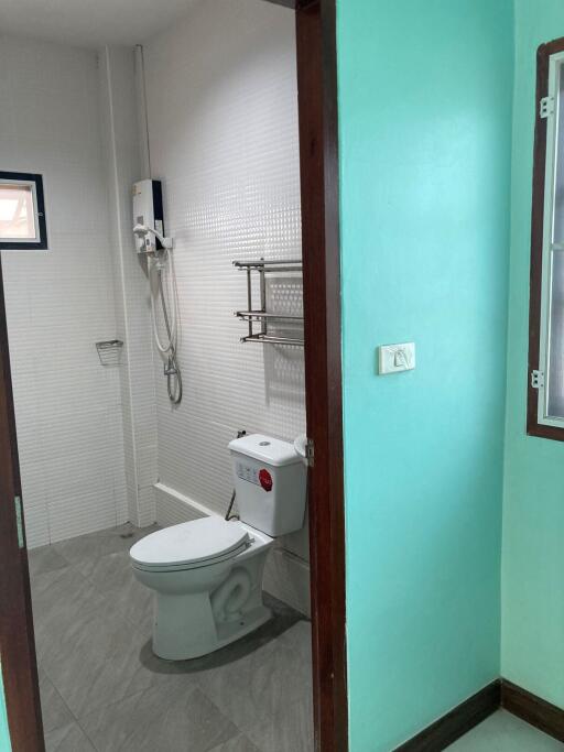 A bathroom with a toilet, shower, and teal walls