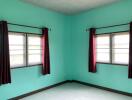 Empty bedroom with two windows and red curtains