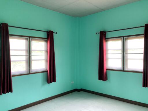 Empty bedroom with two windows and red curtains