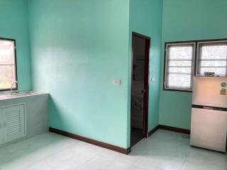 Kitchen with teal walls, window, and fridge