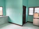 Kitchen with teal walls, window, and fridge