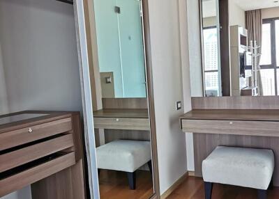 Closet area with wooden furniture, mirror, and small stool