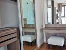 Closet area with wooden furniture, mirror, and small stool